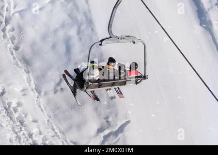 Skifahrer fahren im Skigebiet mit dem Aufzug den Berg hinauf. Skifahren im Winter. Stockfoto