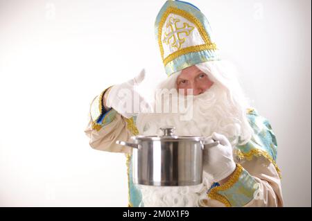 Sinterklaas-Porträt. USA auf weißem Hintergrund. Holländischer Weihnachtsmann St. Nicholas weihnachten Neujahr St. Nicholas mit einem Topf in den Händen bereitet Silvester-Essen für Weihnachten vor Stockfoto
