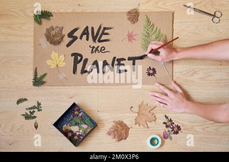 Draufsicht von Frauen, die ein Poster als Aufruf zum Handeln gegen den Klimawandel machen. Stockfoto