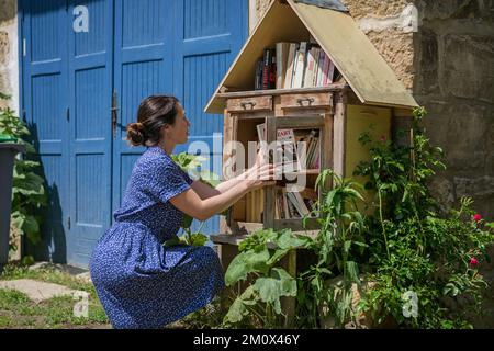 Frau nimmt die kostenlosen Bücher über die Straßenbibliothek Stockfoto