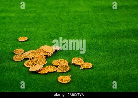 Gefälschte Goldmünzen auf grün, die verstreut auf dem Rasen Stockfoto