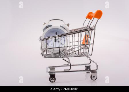 Wecker in einem Einkaufswagen auf weißem Hintergrund Stockfoto