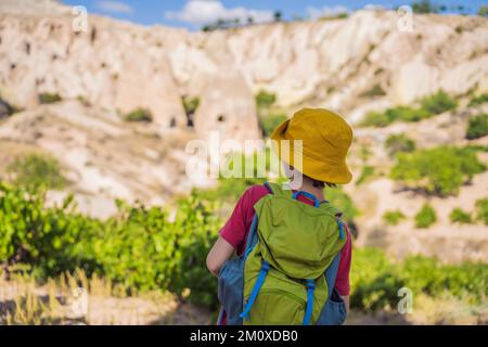 Junge Touristen, die das Tal mit Felsformationen und Feenhöhlen in der Nähe von Goreme in Kappadokien, Türkei, erkunden Stockfoto