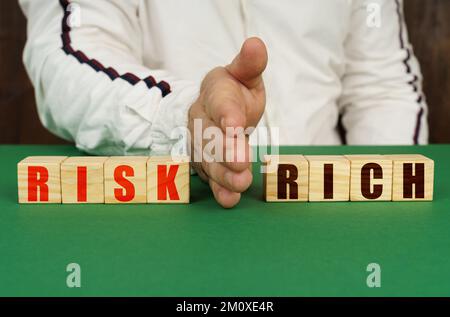 Geschäftskonzept. Ein Mann trennt die Würfel mit der Inschrift - RISIKO oder REICH Stockfoto