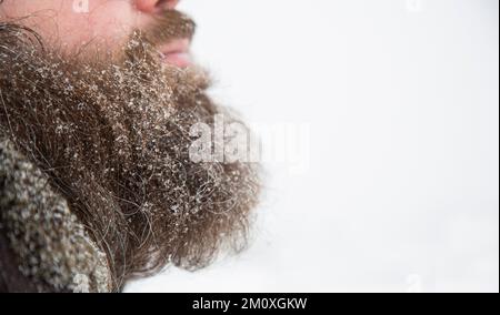 Bärtiger Mann bei Schneewetter auf der Straße im Schnee. Schnee auf dem Bart Stockfoto