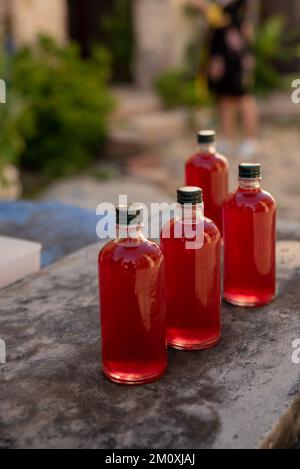 Kleine Glasflaschen gefüllt mit roten Flüssigkeiten, sommerliches Erfrischungsgetränk-Konzept Stockfoto