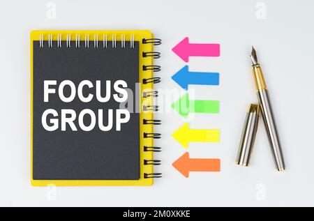 Geschäfts- und Finanzkonzept. Auf weißem Hintergrund liegen ein Stift, Pfeile und ein Notizbuch mit der Aufschrift - FOKUSGRUPPE Stockfoto