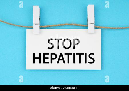 Medizin und Gesundheitskonzept. Auf blauem Hintergrund hängt eine weiße Plakette an einem Seil mit der Inschrift - STOPPT HEPATITIS Stockfoto