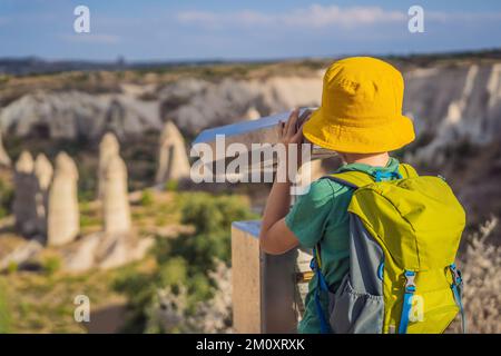 Junge Touristen, die das Tal mit Felsformationen und Feenhöhlen in der Nähe von Goreme in Kappadokien, Türkei, erkunden Stockfoto