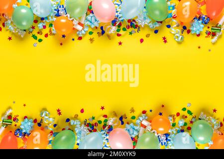 Geburtstagshintergrund, Draufsicht. Rahmen aus Ballons und verschiedenen Partydekorationen auf gelbem Hintergrund Stockfoto