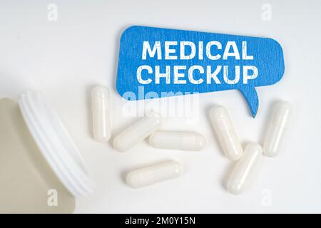 Medizin und Gesundheitskonzept. Auf dem Tisch liegen Pillen und ein blaues Schild mit der Aufschrift "Medizinische Untersuchung" Stockfoto