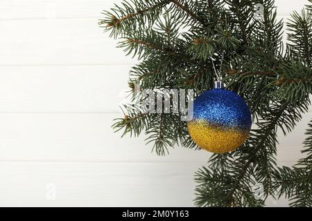 Gelb-blauer Neujahrsball in den Farben der ukrainischen Flagge. Nahaufnahme der gelb-blauen Kugel auf dem Weihnachtsbaum wunderschöner Hintergrund für Desi Stockfoto