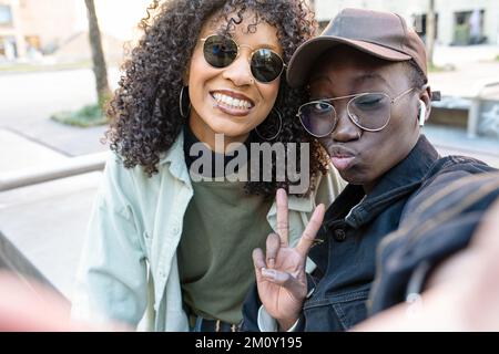 Zwei junge afroamerikanische Frauen machen Selfie, Hip-Hop-Street-Style, Freunde nutzen App Mobile, um sich mit sozialen Medien zu verbinden, positives Image und Gesten Stockfoto