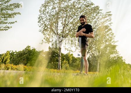 Junger Mann mit künstlichem Beinlaufen und Fitness-Aktivität in einem öffentlichen Park Stockfoto