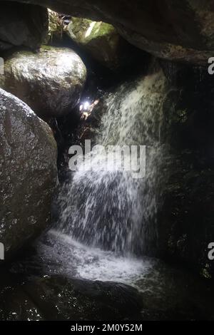 Ein großer Wasserfall neben einem Felsen im Schatten Stockfoto