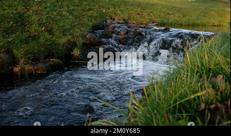 Der Fluss eines Flusses durch eine Steinbarriere. Stockfoto