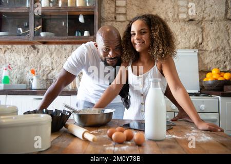 Afroamerikanischer Vater und Tochter kochen gemeinsam in ihrer heimischen Küche ein Dessert Stockfoto