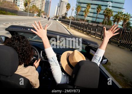 Fröhliches weißes Paar, das an einem sonnigen Tag im Cabrio fährt und die Freiheit in einer Stadt genießt Stockfoto