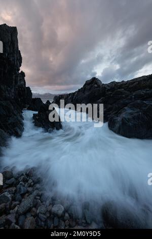 Ankommende Welle fließt über felsige Küsten, Lofoten-Inseln, Norwegen Stockfoto