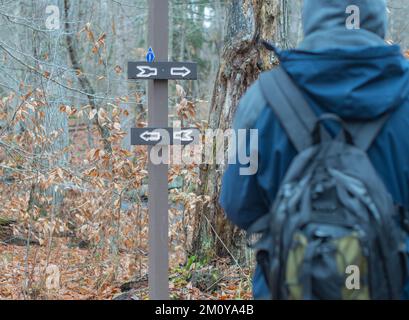 Überqueren Sie die Straßen auf dem Wanderweg, unterschreiben Sie die Entscheidung in welche Richtung Stockfoto