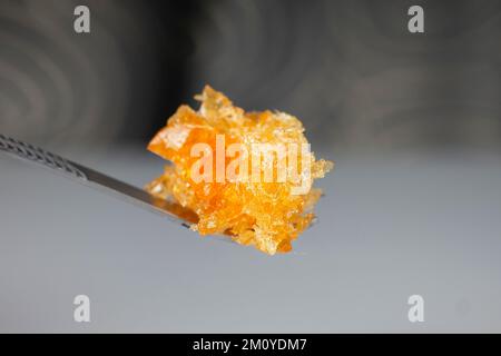 Bernstein-gelbes Cannabiswachskonzentrat tropft aus der Nahaufnahme des Dabbing-Werkzeugs. Stockfoto