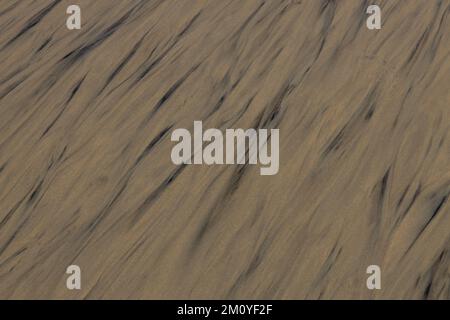 Wellenlinien aus Wasser und Sand. Abstrakter Hintergrund eines Strands. Stockfoto
