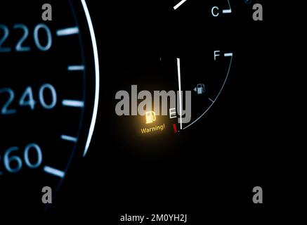 Kontrollleuchte für niedrigen Kraftstoffstand auf dem Armaturenbrett mit darunter liegendem Kopierfeld auf schwarzem Hintergrund Stockfoto
