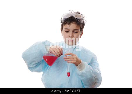 Schuljunge, junger Wissenschaftler und Chemiker im Laborkittel, gießt rote flüssige chemische Substanz durch einen Glastrichter in das Reagenzglas Stockfoto