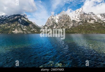 Schneebedeckte Berge über dem klaren blauen Wasser des Jenny Lake im Grand Teton National Park, Wyoming Stockfoto