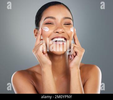 Diese rosigen Wangen bleiben feuchtigkeitsspendend. Eine schöne junge Frau, die sich eine Feuchtigkeitscreme ins Gesicht legt. Stockfoto