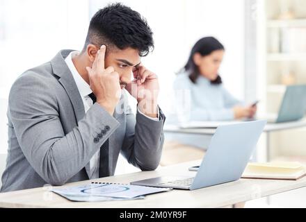 Ich muss mich nur konzentrieren... ein junger Geschäftsmann, der gestresst aussieht, während er an einem Notebook im Büro arbeitet. Stockfoto