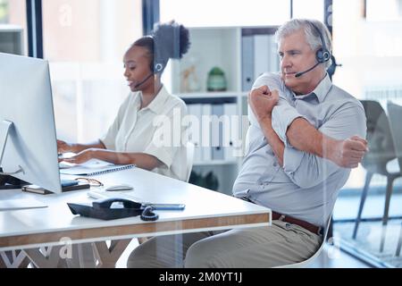 Ich muss in Bewegung bleiben und die ganzen großen Verkäufe machen. Ein ausgereifter Callcenter-Agent, der während der Arbeit im Büro die Arme ausstreckt. Stockfoto