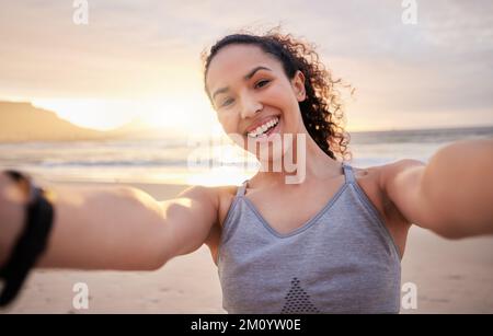 Ich lasse ein paar Endorphine am Strand frei. Eine fitte junge Frau, die ein Selfie am Strand macht. Stockfoto