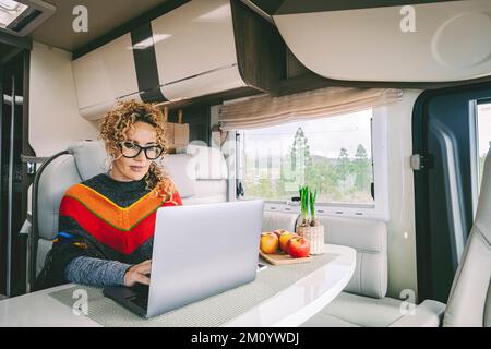 Unabhängige Frau, die in einem Wohnmobil sitzt, bei einer intelligenten Remote-Arbeitsaktivität mit einem Laptop. Konzept der digitalen Nomadenfreiheit Lebensstil mit weiblichem p Stockfoto