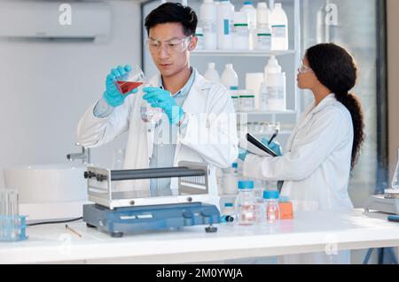 Hier findet die harte Arbeit statt. Ein junger männlicher Labortechniker, der Proben im Labor füllt. Stockfoto