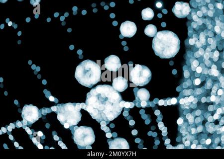 Unscharfer Hintergrund. Wunderschöne leuchtende und blinkende Silvester- und Weihnachtsdekoration Girlanden und glühende Kugeln für die Nacht zum Aufhängen des Weihnachtsbaums. Verschwommene blinkende Bokeh-Flecken im Hintergrund Blau Stockfoto