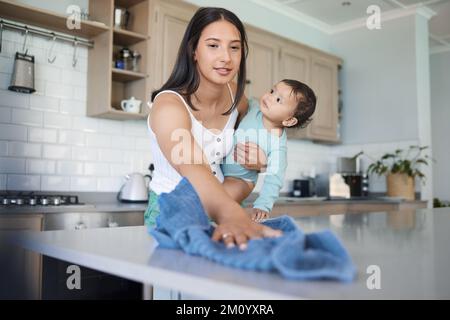 Wie machst du das, mom? Eine Frau, die ihr Haus putzt, mit ihrem Baby am Arm. Stockfoto