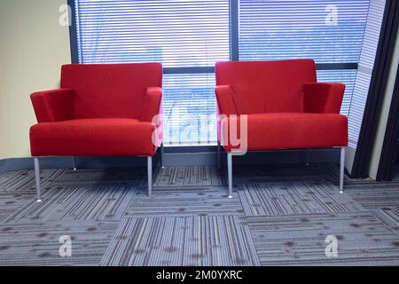 Zwei rote Stühle in einem Bürogebäude, Teppich an einem Fenster Stockfoto