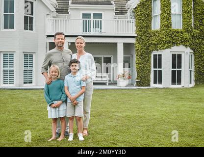 Zuhause ist kein Ort, es ist ein Gefühl, das die Familie einem gibt. Ein Paar steht draußen mit seinen beiden Kindern. Stockfoto