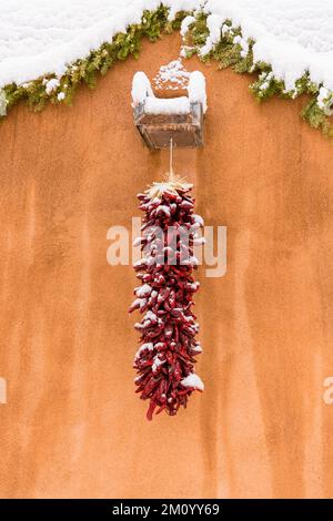 Winterweihnachtsszene einer schneebedeckten roten chilenischen Ristra in Santa Fe, New Mexico Stockfoto