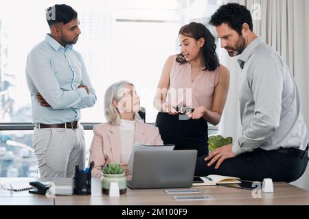 Ich habe vielleicht eine Idee. Eine vielfältige Gruppe von Geschäftsleuten, die während einer Besprechung im Büro einen Laptop verwenden. Stockfoto