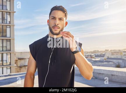 Nichts bringt Sie dazu, sich wie Musik zu bewegen. Ein Mann, der Kopfhörer trägt, während er draußen in Trainingskleidung steht. Stockfoto