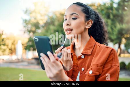Zeit für eine Auffrischung. Eine Frau, die sich in einem Park schminkt. Stockfoto