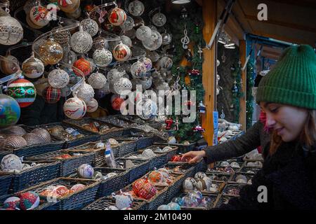 Die Leute wählen die Weihnachtsdekoration im Kiosk des Weihnachtsmarkts aus Stockfoto
