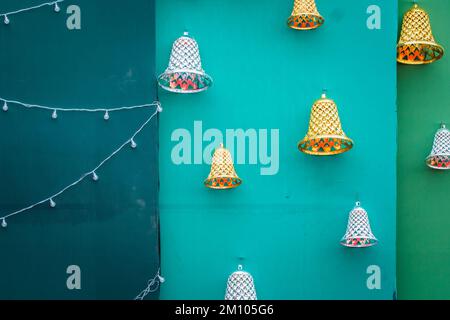 Satz goldener Weihnachtsglocken mit silbernen Glocken und Serienlampen isoliert auf grünem Hintergrund. Stockfoto