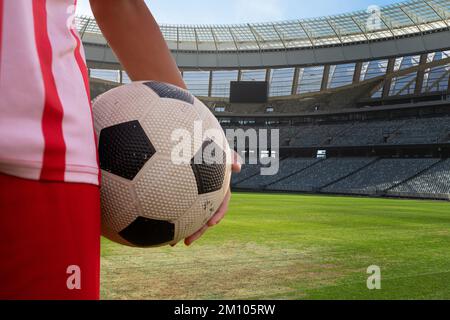 Mitte des Spielers, der an sonnigen Tagen Fußball im Stadion hält, Kopierraum. Fußball, Sportler, Sportler, Sport, Wettkampfsport, Spiel, Geschick. Stockfoto