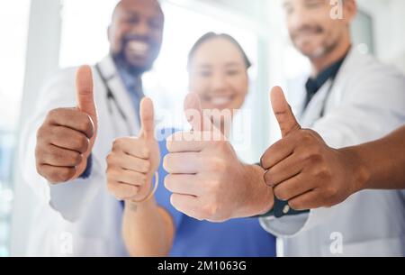 Sie stehen an erster Stelle in der medizinischen Welt. Eine Gruppe von Ärzten, die im Büro Daumen nach oben zeigen. Stockfoto