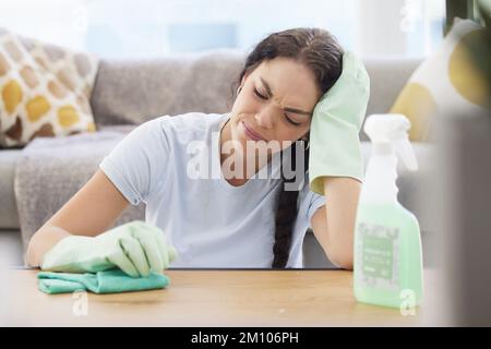 Zimmermädchen, Depressionen und Frauen, die müde sind, wenn sie Möbel putzen, Staub und Schmutz im Wohnzimmer des Apartments. Hausarbeit, Frühjahrsputz und traurig Stockfoto