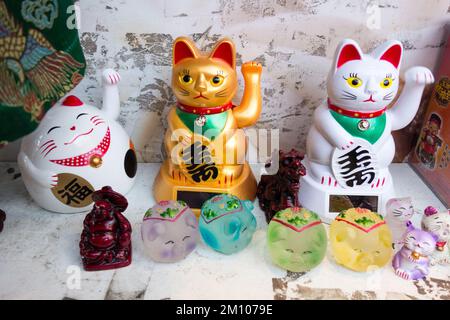 Nahaufnahme von Maneki Neko (japanische Weckkatzen) in einem Restaurantfenster in China Town, Soho, London, England, Großbritannien Stockfoto