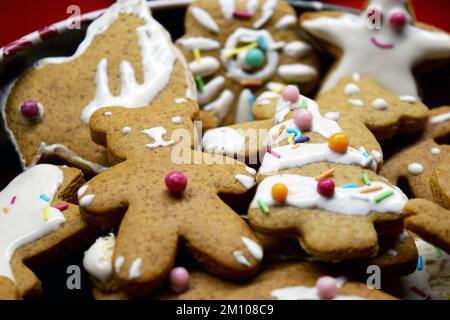 Süßes Lebkuchen hausgemachte Figuren zu Weihnachten, dekoriert mit weißem Glasur und farbigen Süßigkeiten: teddybären, Lebkuchen-Mann, Weihnachtsbaum, Sterne. Stockfoto